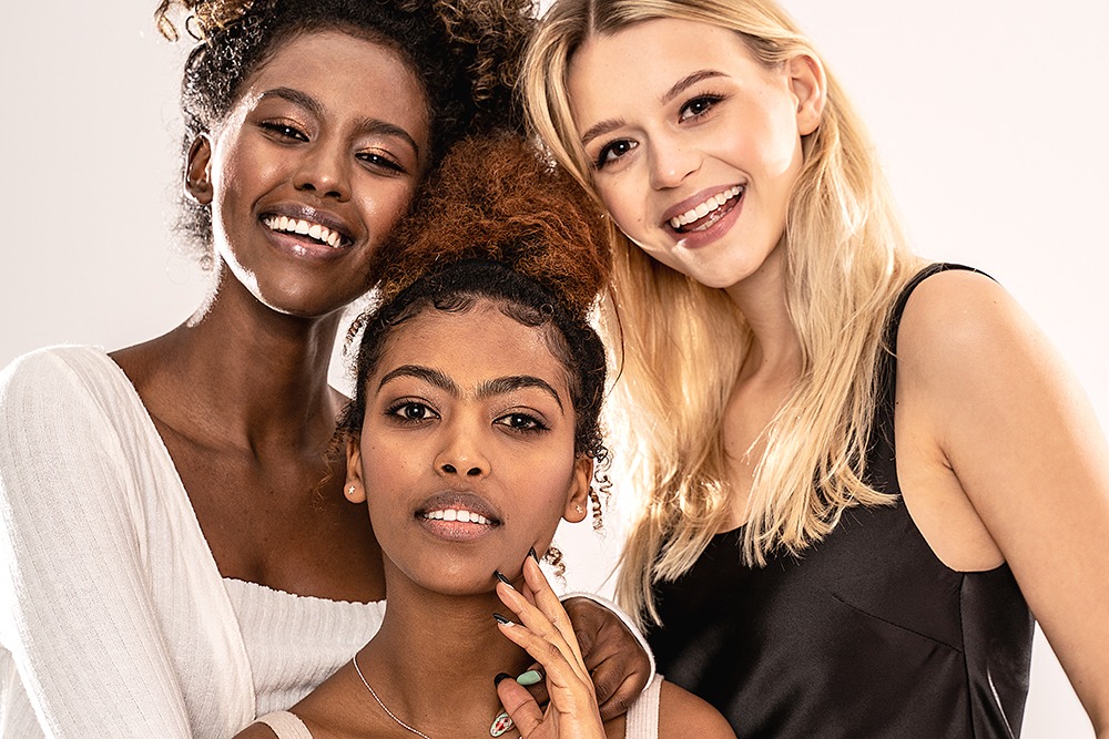 Three attractive young multiethnic women looking at camera, smiling